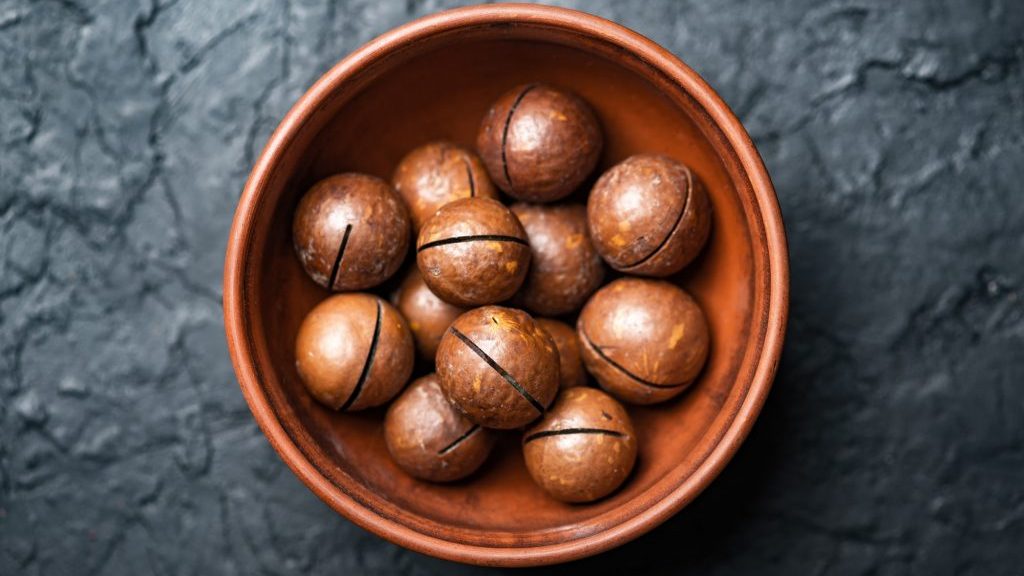 Dried organic Macadamia nuts in orange ceramic bowl