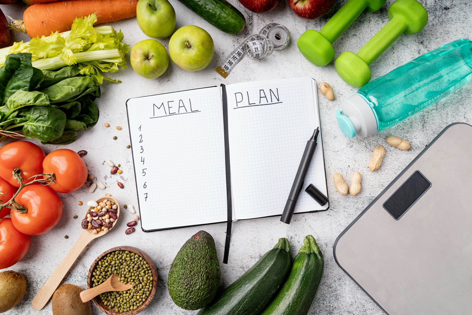 Weight lose and dieting concept. Notepad with words Meal Plan with healthy foods and sport equipment